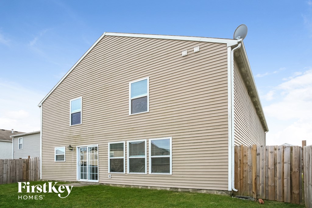 the back of a house with a wooden fence and grass
