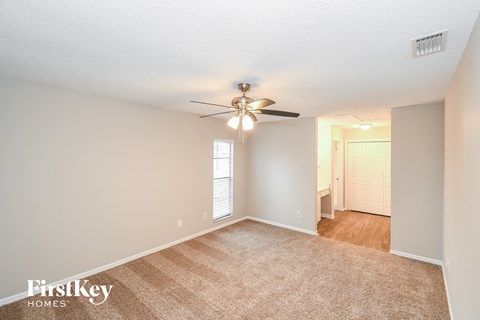 a spacious living room with a ceiling fan and a rug