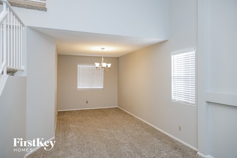 a spacious living room with beige carpet and white walls