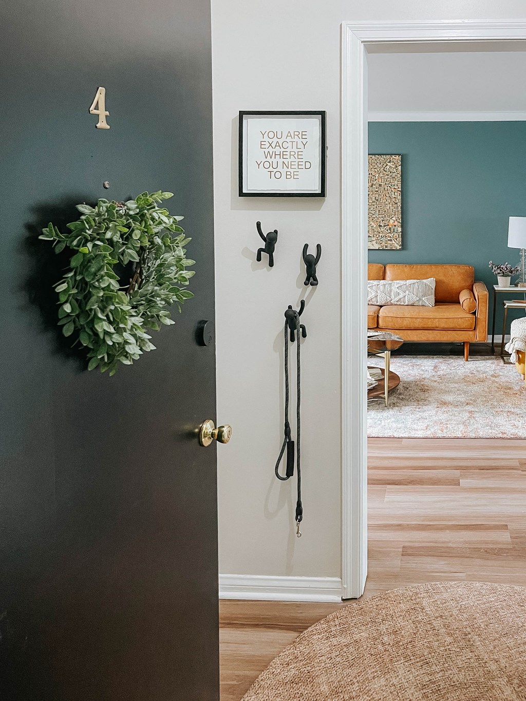 a living room with a door open and a wreath on the wall
