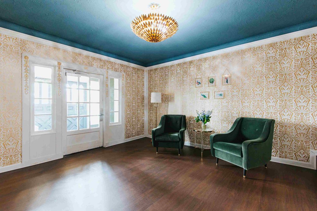 a living room with two green chairs and a chandelier