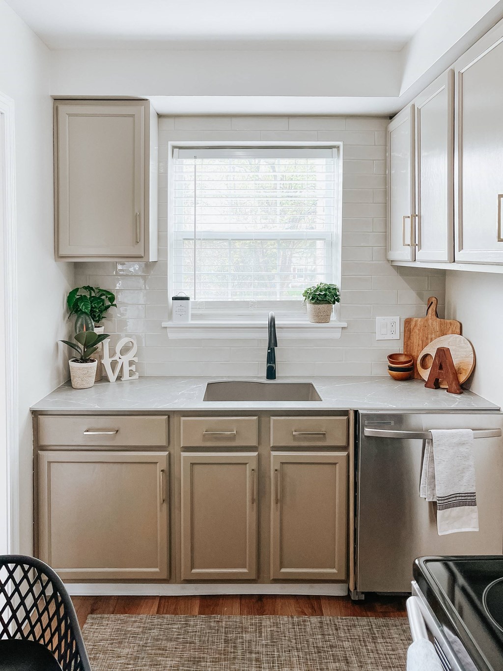 a kitchen with white cabinets and a sink and a window