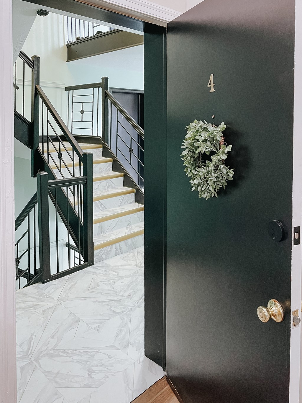 the front door of a house with stairs and a christmas wreath on it