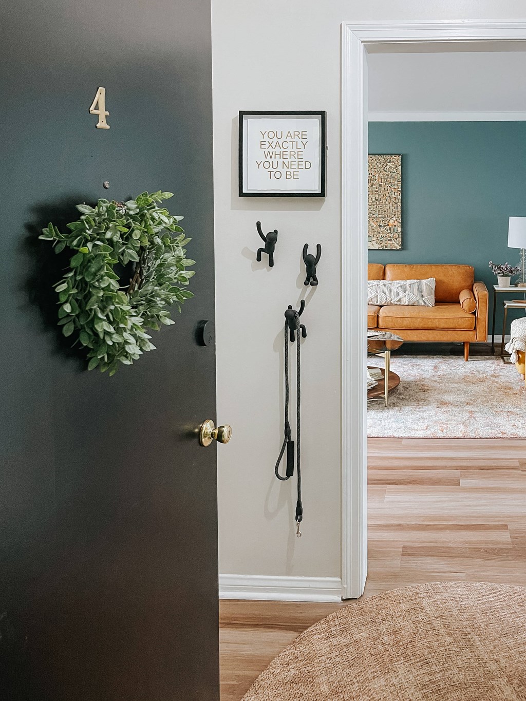 a living room with a door open and a wreath on the wall