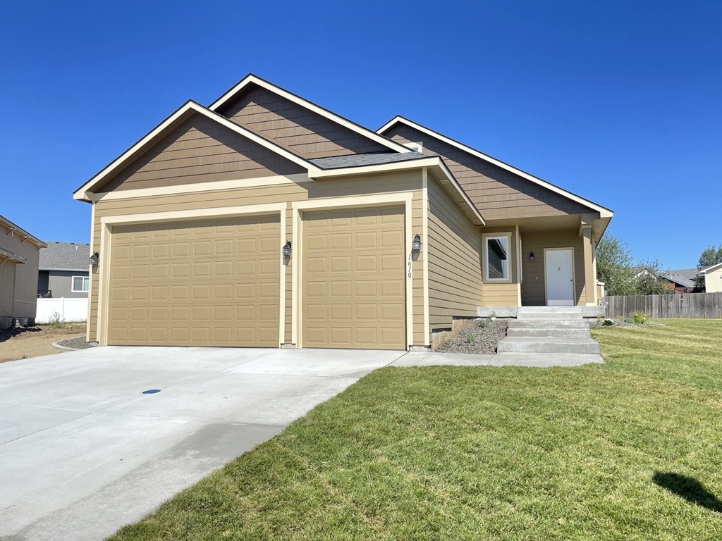a tan house with a garage door and a driveway