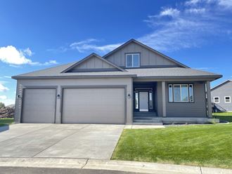 a gray house with a garage door and a lawn