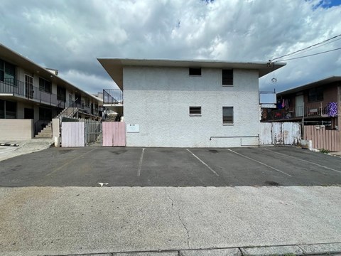 A white building with a pink door in the middle of a parking lot.