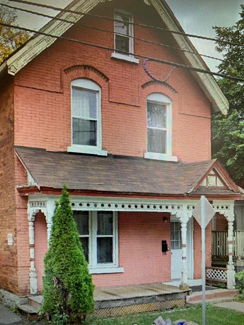 A red brick house with a white door and a small porch.