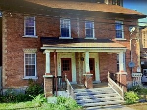A red brick house with a porch and a front door.