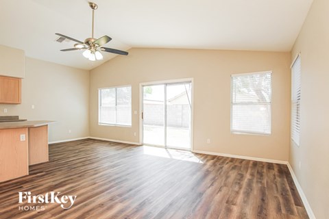 A spacious room with wood flooring and a ceiling fan.