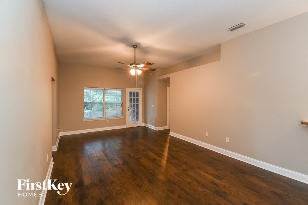 an empty living room with wood floors and a ceiling fan