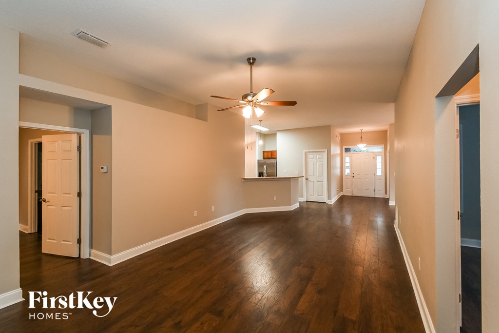 an empty living room with wood floors and a ceiling fan