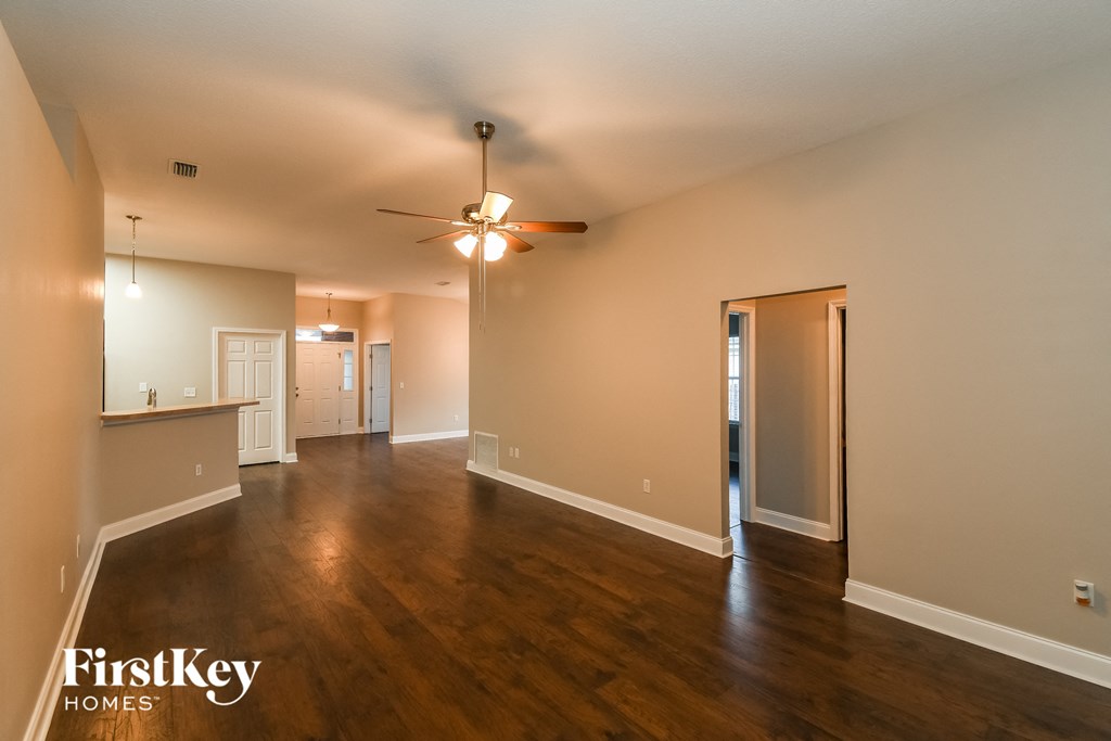 an empty living room with wood floors and a ceiling fan