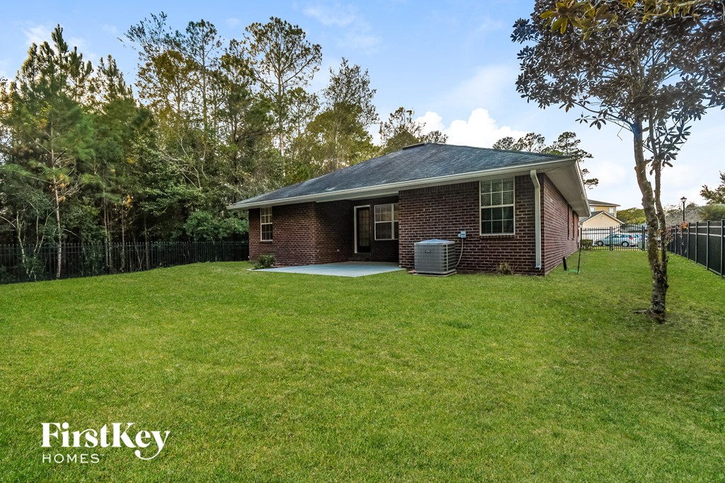a small brick house with a yard and a fence