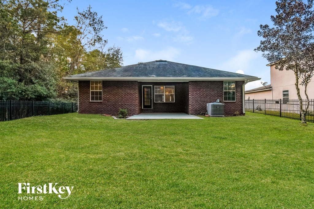 a small brick house with a yard and a black fence