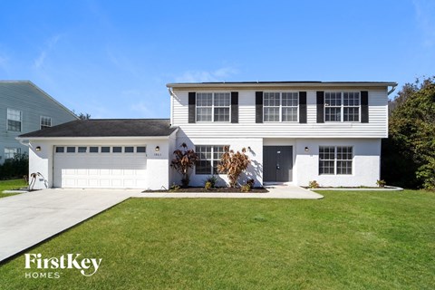 a white house with a garage door and a lawn