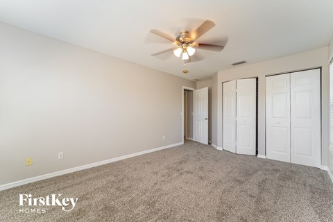 a spacious living room with carpet and a ceiling fan