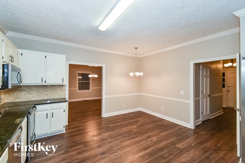 A kitchen with white cabinets and a wooden floor.