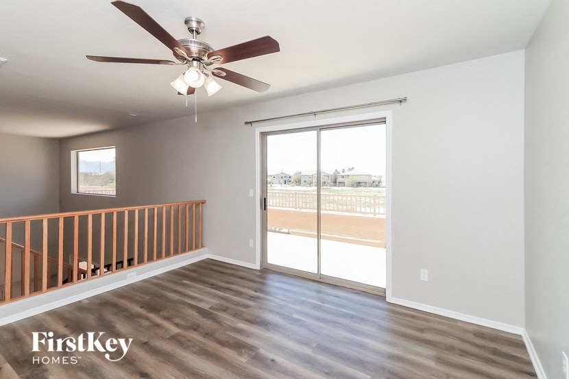 A room with a ceiling fan and sliding glass doors.