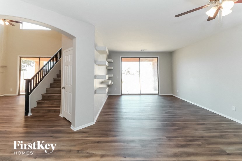 A spacious room with wooden floors and a staircase leading to another room.