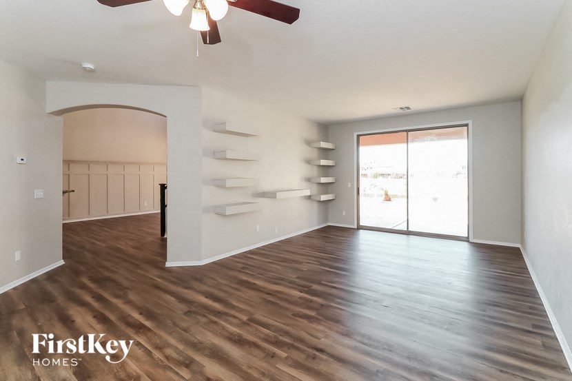 A spacious room with wooden flooring and a ceiling fan.