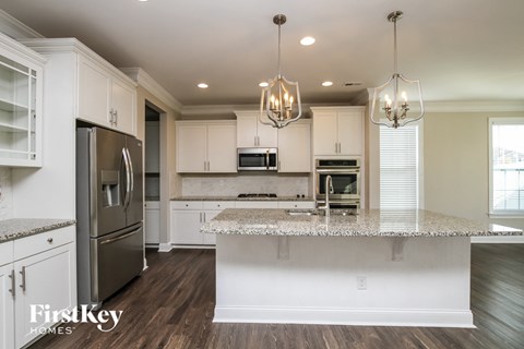 a kitchen with white cabinets and a marble counter top