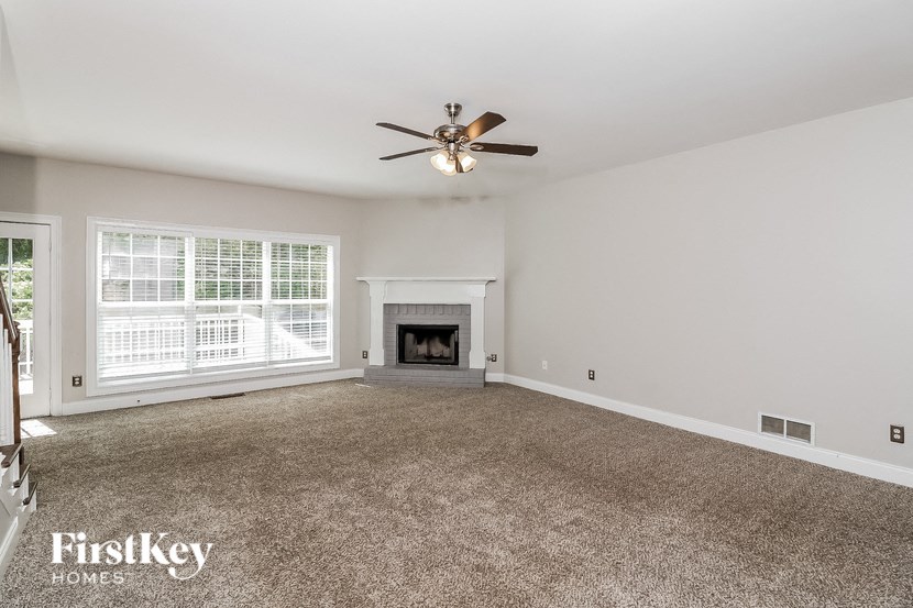 an empty living room with a ceiling fan and a fireplace