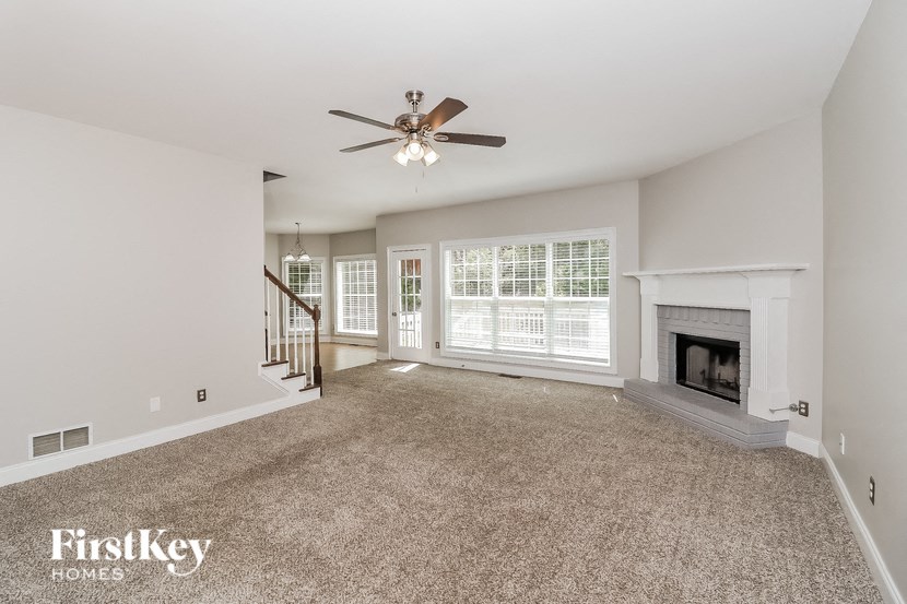 an empty living room with a ceiling fan and a fireplace