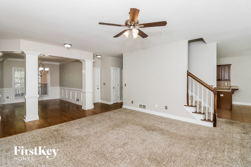 an empty living room with a ceiling fan and a staircase