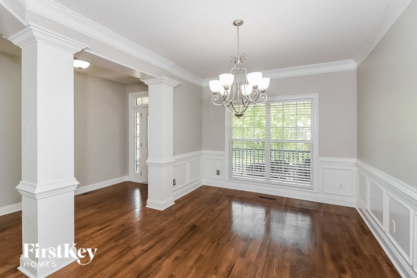 an empty dining room with a large window and a chandelier