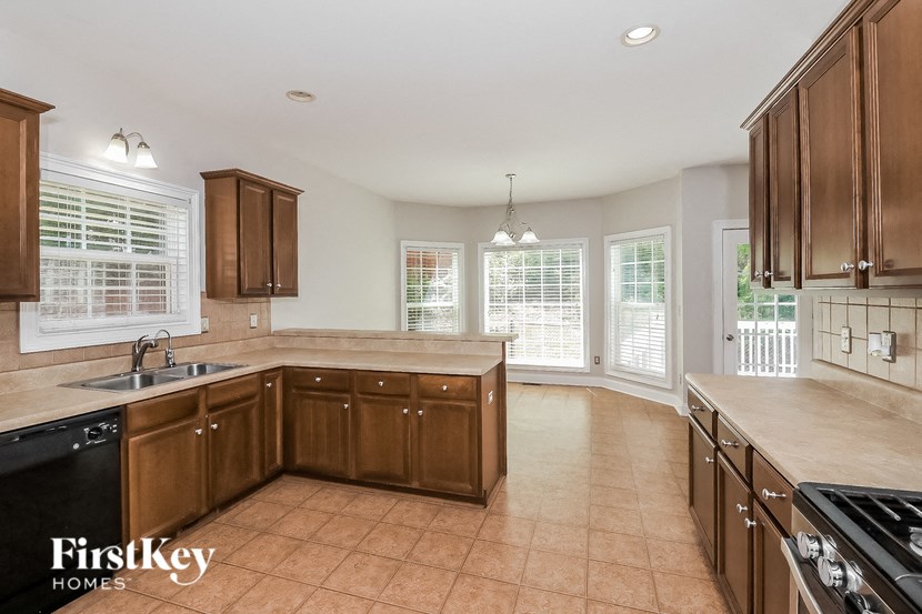 a large kitchen with wooden cabinets and tile flooring and a sink