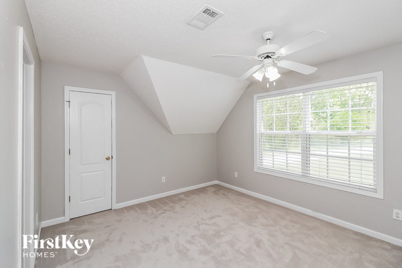 an empty bedroom with a ceiling fan and a window