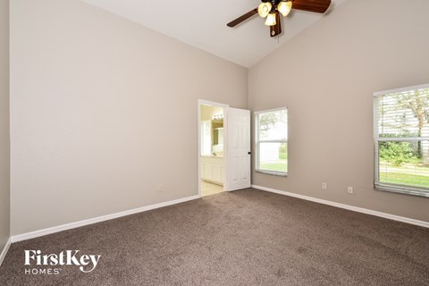 the living room of a house with carpet and a ceiling fan