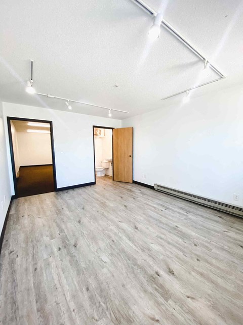 an empty room with white walls and wood floors