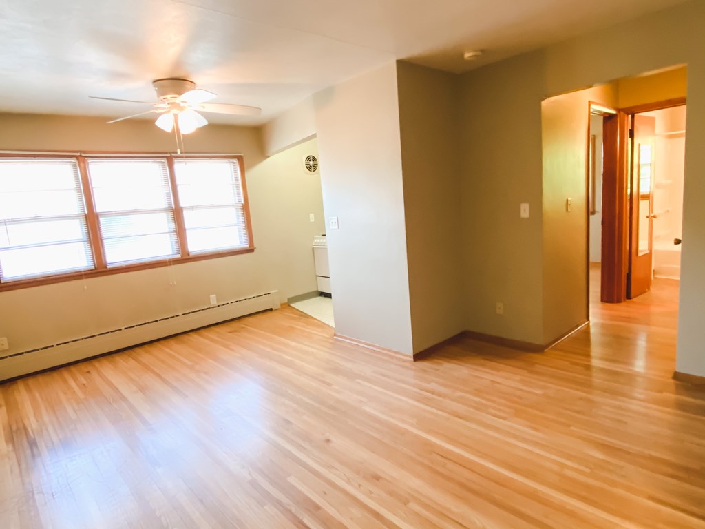an empty living room with wood floors and a window