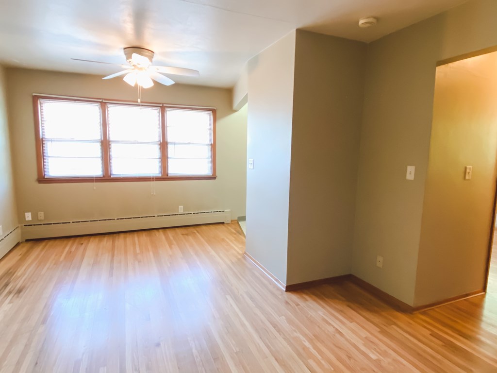 a living room with wood floors and a window and a ceiling fan