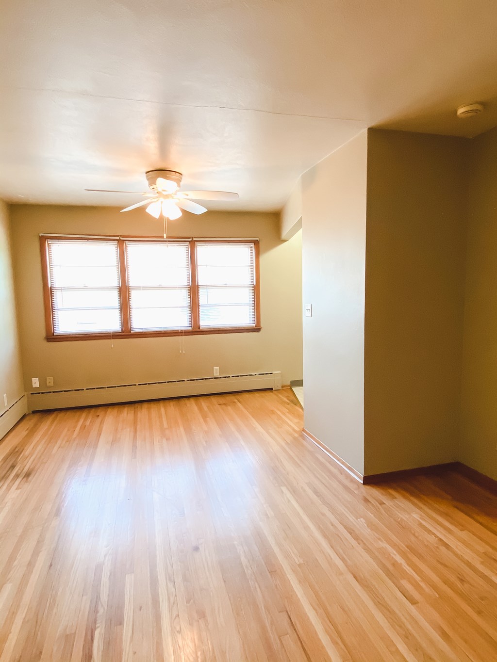 an empty living room with wood floors and a ceiling fan