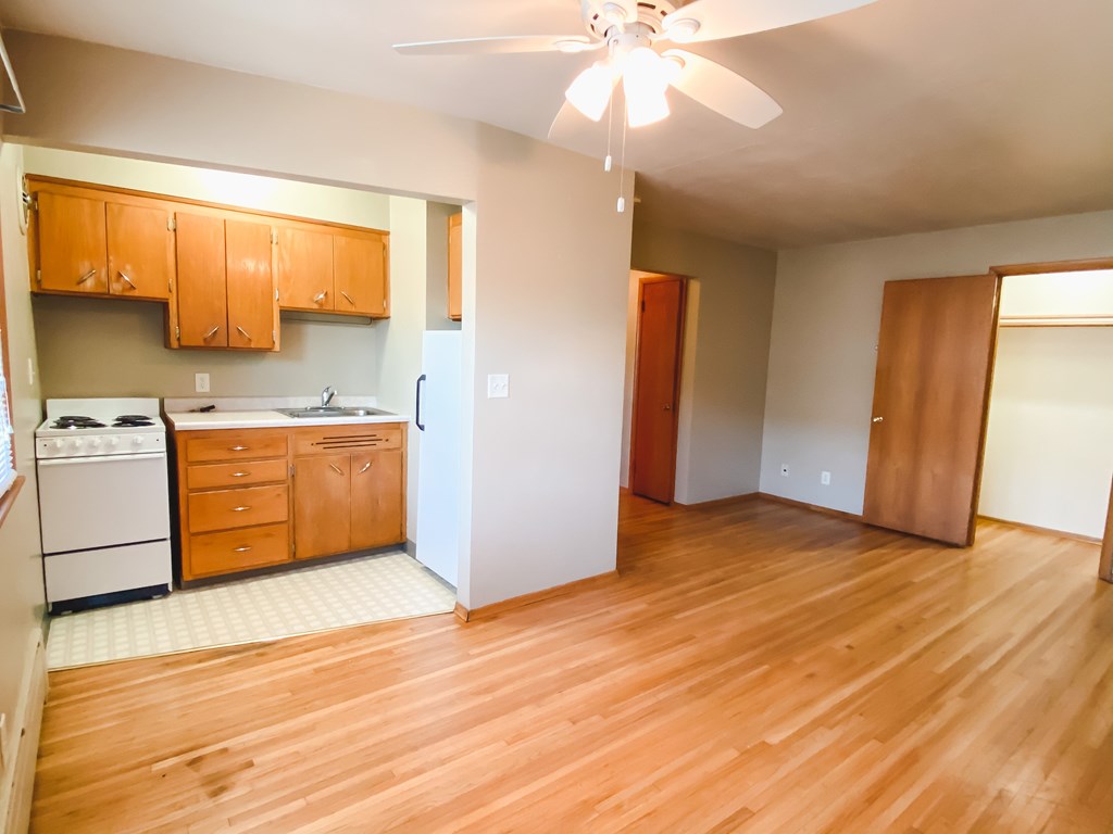 an empty kitchen with wood flooring and a ceiling fan