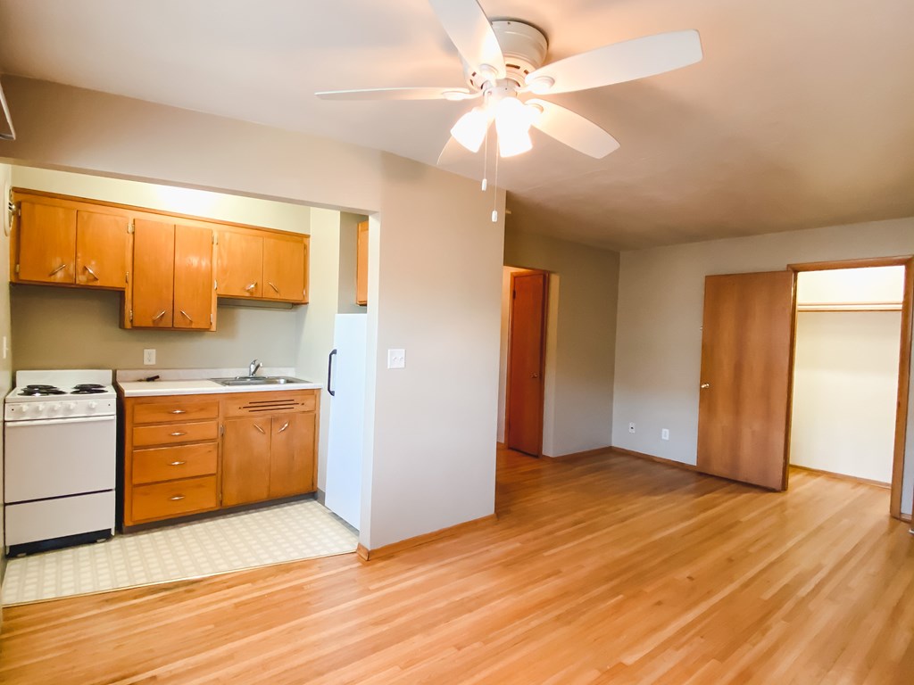 an empty kitchen with wood flooring and a ceiling fan