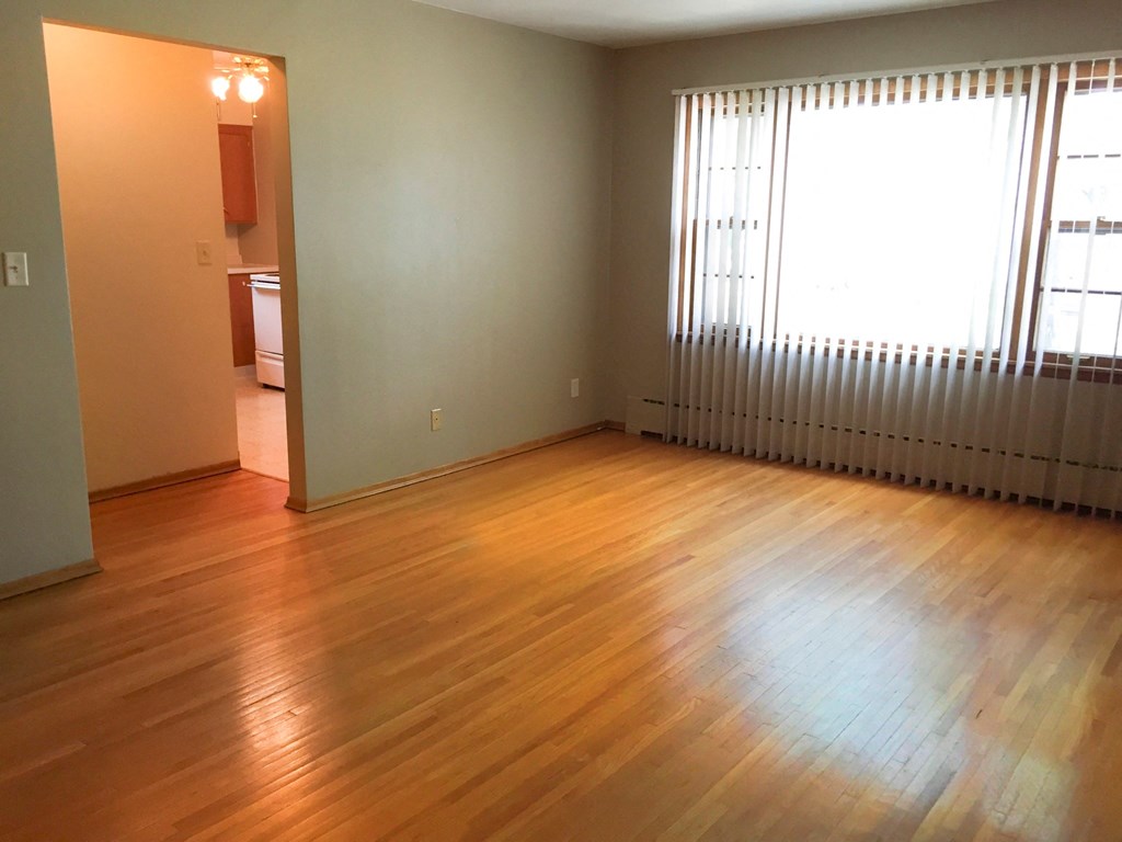 an empty living room with wood floors and a window