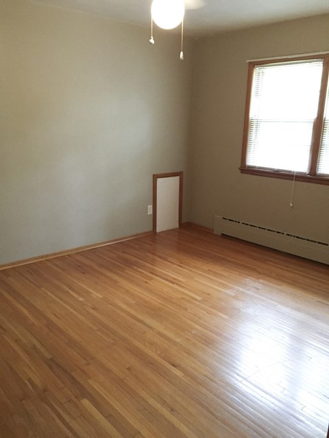 an empty room with wooden floors and two windows