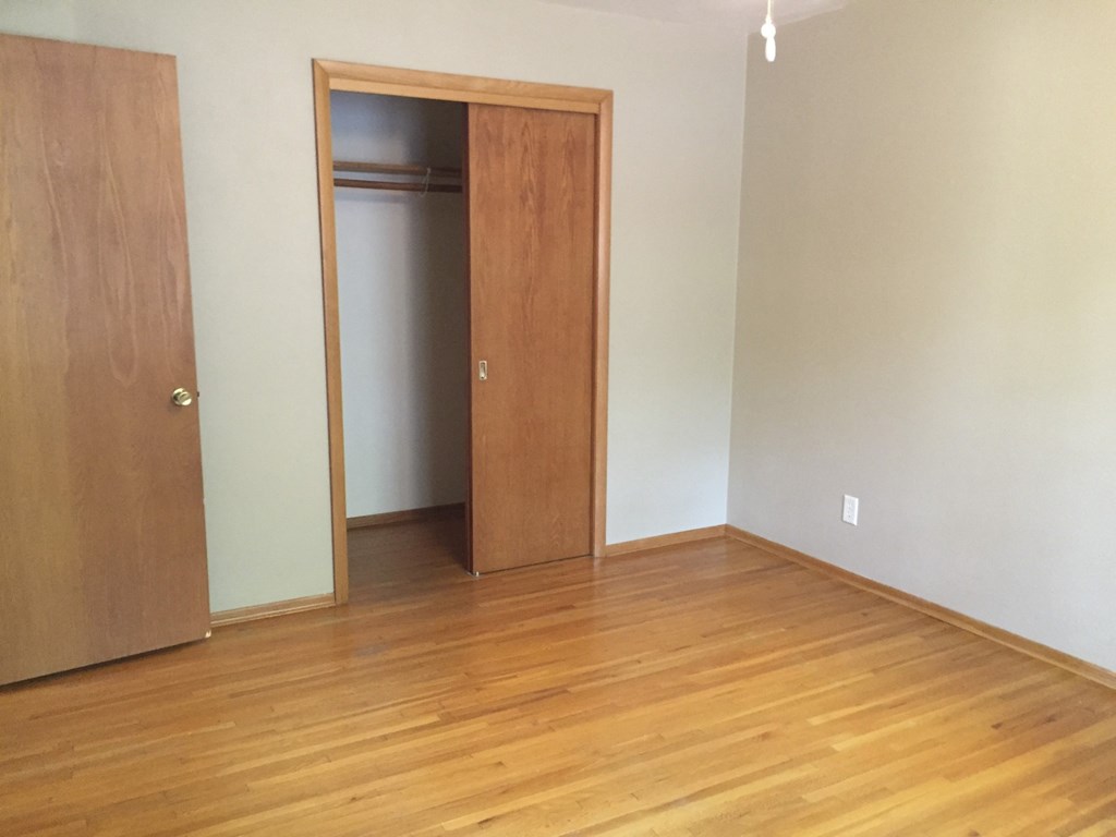 an empty living room with wood floors and a closet