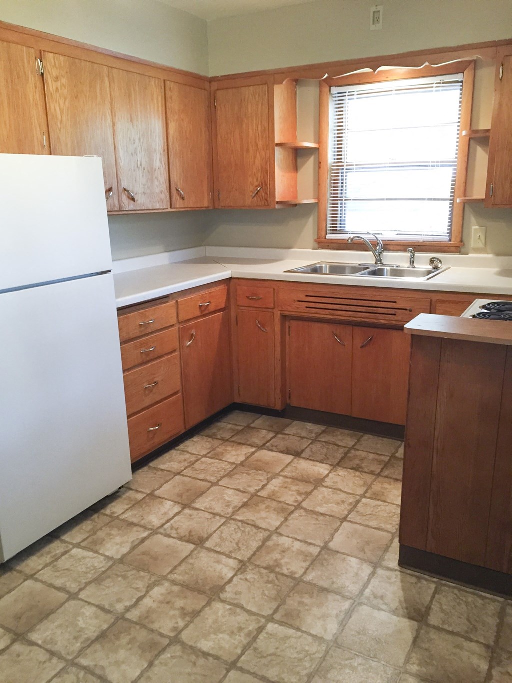 an empty kitchen with wooden cabinets and a white refrigerator