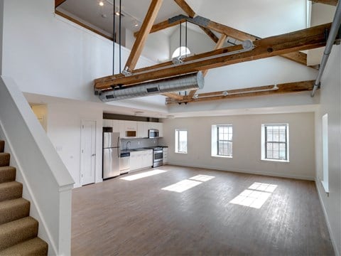 an open living room with a kitchen and exposed beams in the ceiling
