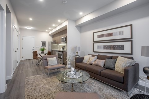 A modern living room with a brown couch and a glass coffee table.