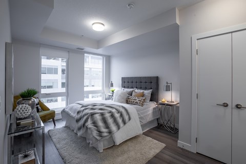 A bedroom with a bed, a chair, and a window.