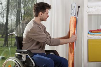 man in a wheelchair grabbing an ironing board