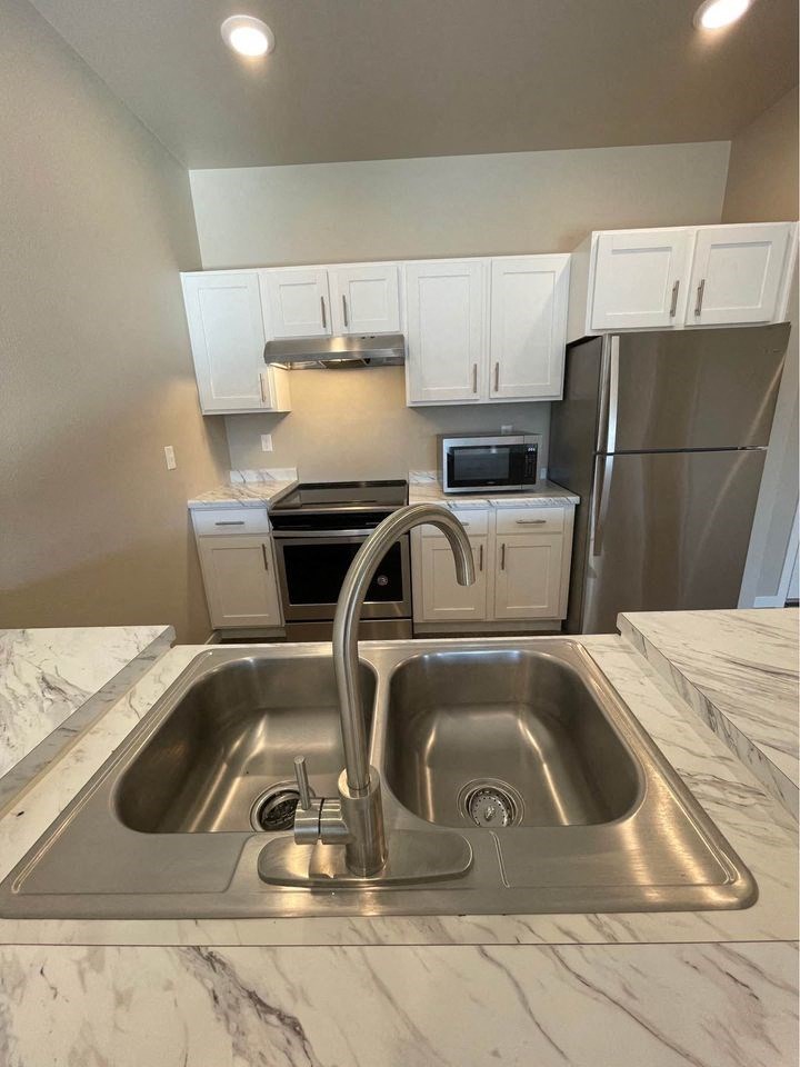 a kitchen with a sink and a stainless steel refrigerator