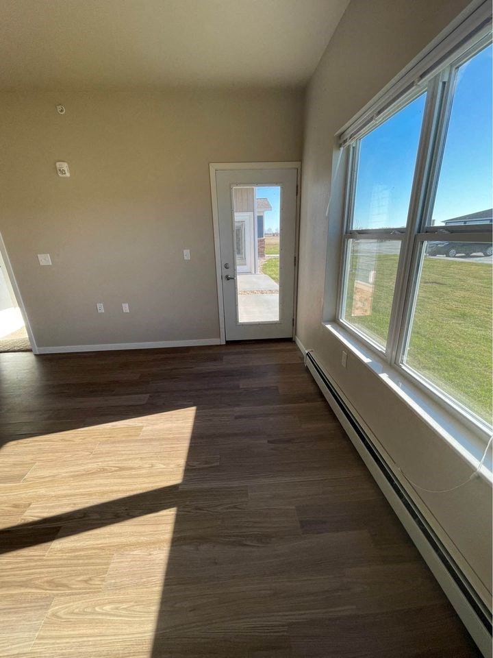 an empty living room with large windows and wood floors