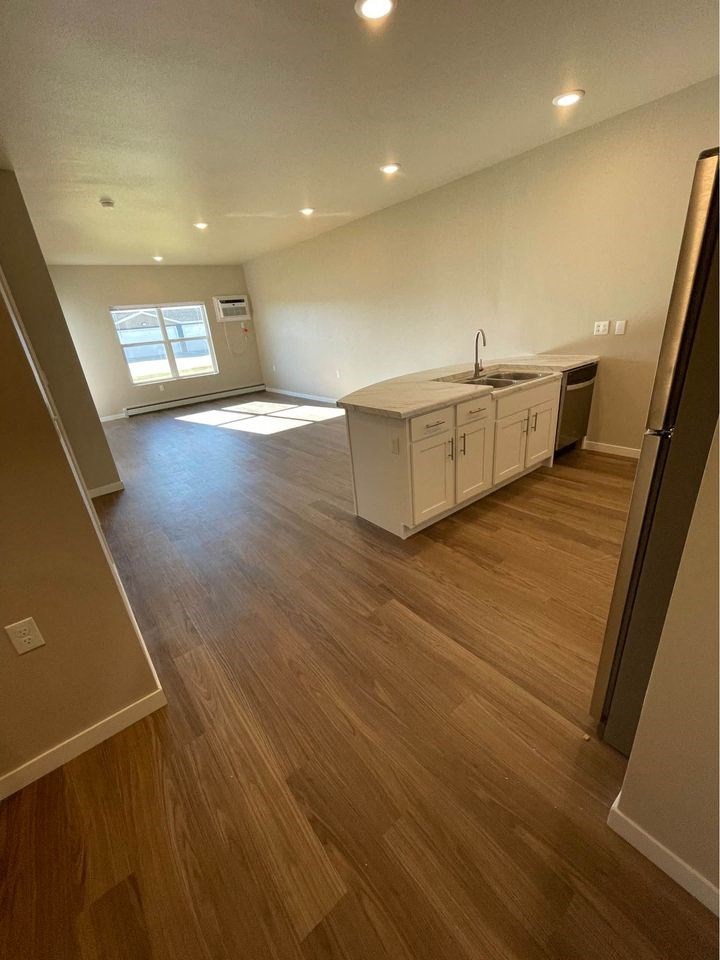 an empty living room and kitchen with wooden floors